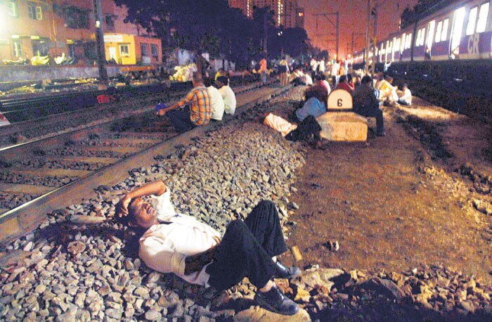 Without the fear of being run over by any local train, a passenger sleeps on the railway track. (Image Courtesy: Mid-Day.com)