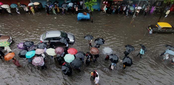 People wade through a flooded street after heavy downpour in Mumbai.