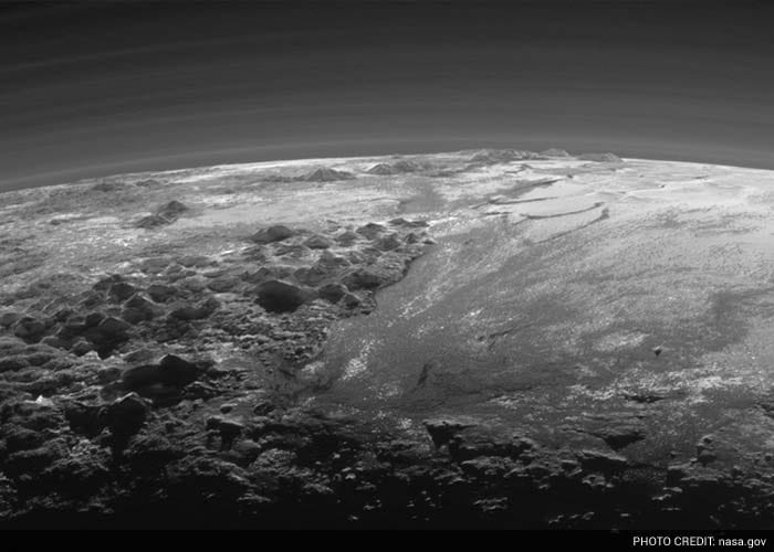 The smooth expanse of the informally named icy plain Sputnik Planum (right) is flanked to the west (left) by rugged mountains up to 11,000 feet (3,500 meters) high, including the informally named Norgay Montes in the foreground and Hillary Montes on the skyline. To the right, east of Sputnik, rougher terrain is cut by apparent glaciers. The backlighting highlights over a dozen layers of haze in Pluto's tenuous but distended atmosphere.(NASA/JHUAPL/SwRI)