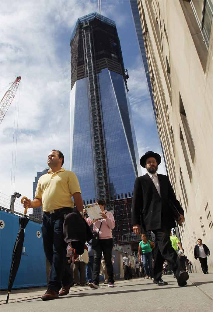 People walk beneath the rising One World Trade Centre as construction continues on September 8, 2011 in New York City.<br><br>A decade after the terrorist attack on the World Trade Centre in New York City, Americans prepare to see a very different Ground Zero, where the construction of new towers is underway leading up to the 10th anniversary memorial.(AFP Photo)