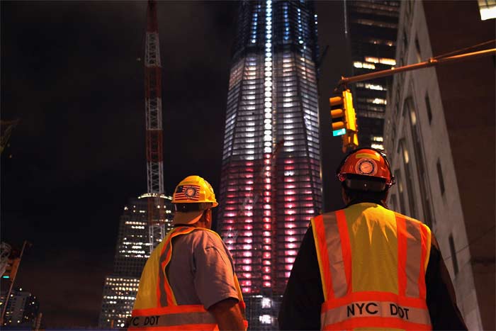 Construction workers look up at the Freedom Tower at the World Trade Centre site which is lit in red, white and blue on September 8, 2011 in New York City. (AFP Photo)