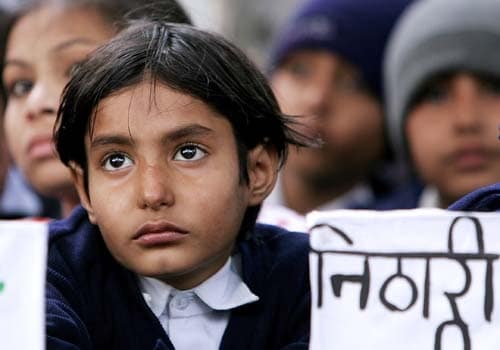 Children hold placards as they take part in a protest against the serial killing of children at Noida on January 11, 2007. (AFP Photo)