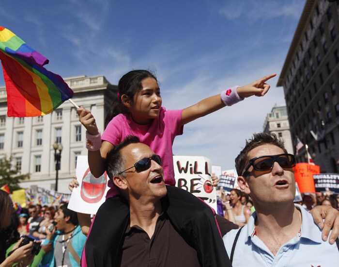 A young girl points out the US Capitol Building to her two fathers during the National Equality March in Washington, Sunday, October 11, 2009.