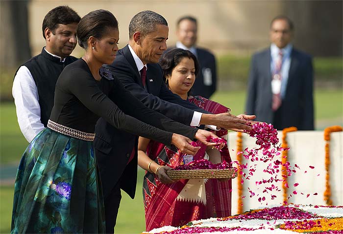 US President Barack Obama (C) and First Lady Michelle Obama (L) spread rose petals after participating in a wreath laying ceremony at Raj Ghat, the memorial to independent leader Mahatma Gandhi, in New Dehli on November 8, 2010. (AFP Photo)