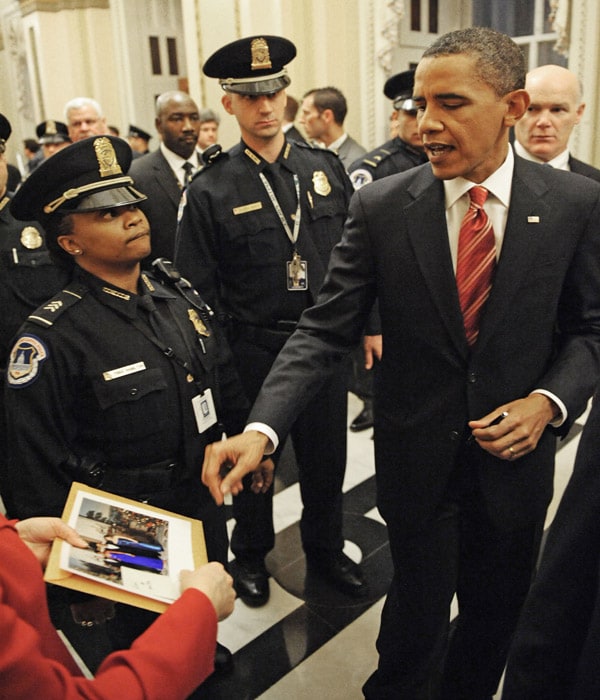 US President Barack Obama prepares to sign an autograph as he walks the US Capitol halls after his first State of the Union speech to a joint session of Congress on Wednesday. (AFP Photo)