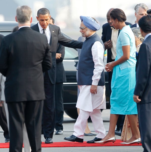 U.S. President Barack Obama and First Lady Michelle Obama walk with Indian Prime Minister Manmohan Singh as they arrive in New Delhi. (AP Photo)