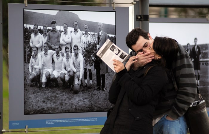 <b>FOR OLD TIMES SAKE: </b>A couple kisses in front of a photograph of France's 1930's soccer team. One thing common between that WC and this one....France did not win then...and the controversy stricken team has been knocked out this time too! (AP Photo)