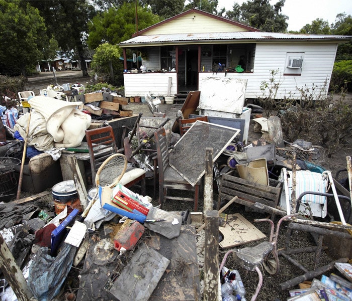 <b>The aftermath:</b> Mud-caked debris is piled in front of a house at Condamine, Australia, after floodwater washed away or ruined household items from hundreds of homes, Friday, Jan. 7, 2011. Some victims of Australia's worst floods in decades returned to their homes to find them caked in sludge as others nervously watched the skies for more rain and waited for swollen rivers to recede. (AP Photo)
