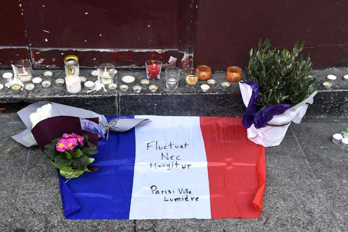 Flowers, candles and the French national flag with the Latin, "Tossed but not sunk" the motto of Paris written on it, is laid outside of the Carillon, adjacent to the Cambodian restaurant on Rue Alibert in the 10th district. (AFP Photo)