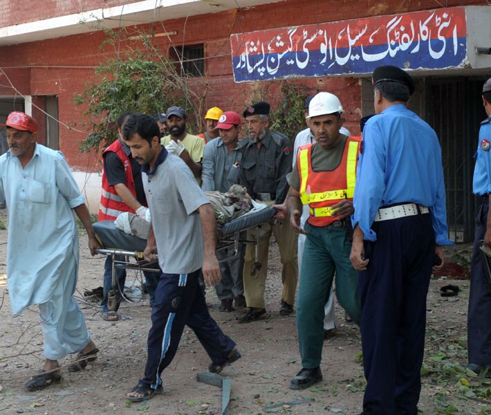 Pakistani policemen and volunteers remove a body from the site of the attack. Three security personnel were among the injured, said district administration chief Sahibzada Muhammad Anees. (AFP)