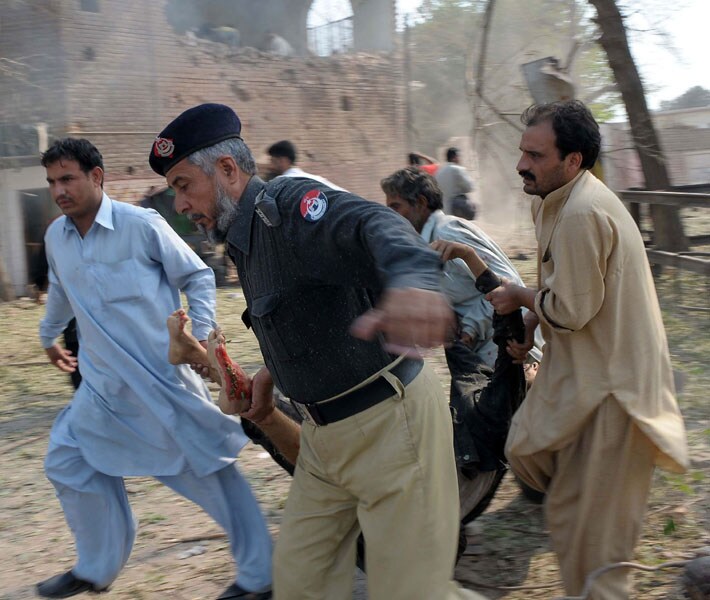 A Pakistani policeman and bystanders remove an injured victim. The attack came a day after the eastern city of Lahore witnessed three near-simultaneous strikes on a Federal Investigation Agency office and two police training centres that killed several people. (AFP)