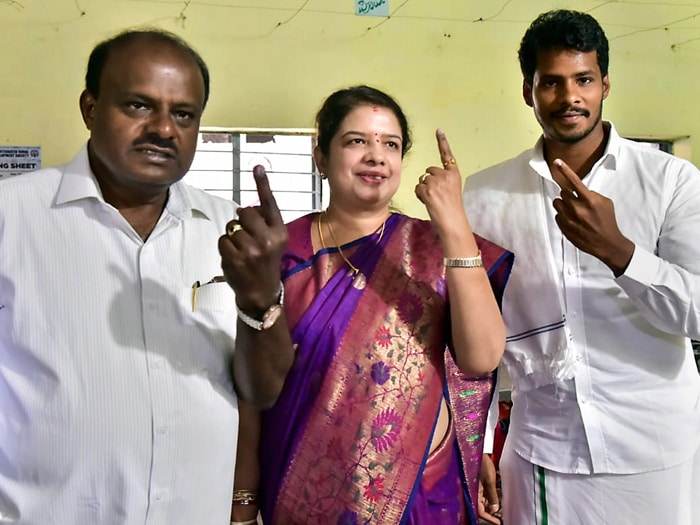 Karnataka Chief Minister HD Kumaraswamy along with wife Anitha Kumaraswamy (C) and son Nikhil Gowda (R) show their finger marked with indelible ink after casting vote for the second phase of the general elections, at a polling station, Kethiganahalli in Ramanagara district.