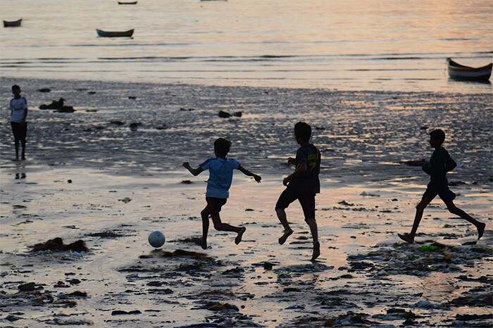 Children play football at a beach in Mumbai.