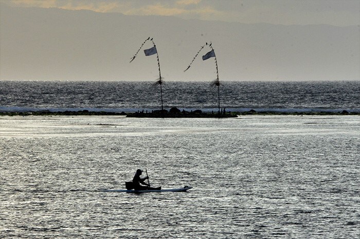 A man paddles a canoe during sunrise at a beach in Sanur on Indonesia's resort island of Bali.