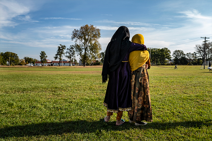 Afghan refugee girls watch a soccer match near where they are staying in the Village at the Ft. McCoy US Army base.