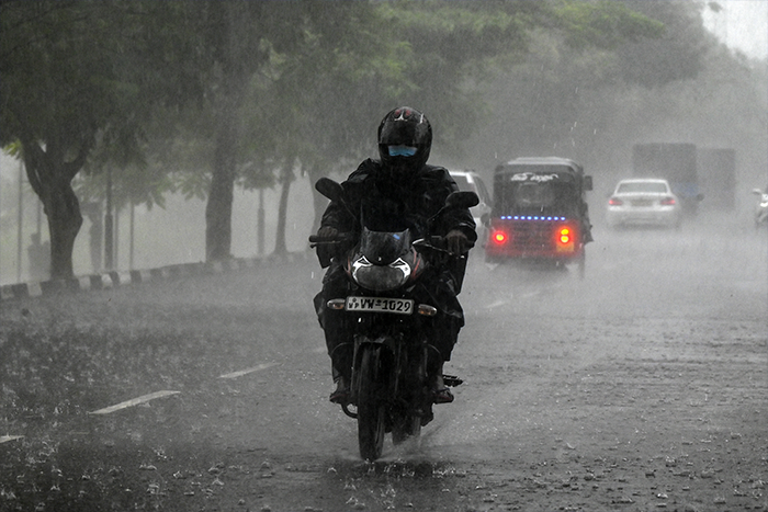 A motorist rides through a road during a heavy rain shower in Colombo.