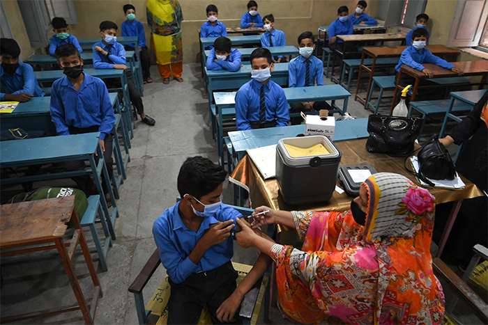 A health worker inoculates a student with a dose of the Pfizer vaccine against the Covid-19 coronavirus at a school in Lahore.