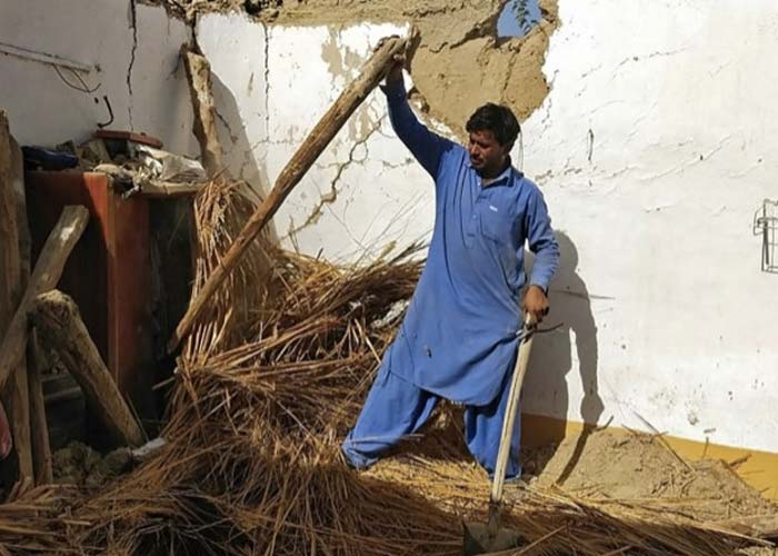 A resident removes debris of his mud house that collapsed following an earthquake in the remote mountainous district of Harnai, Pakistan.