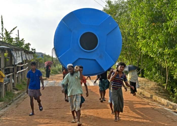 Rohingya refugees carry a water tank at Kutupalong refugee camp in Ukhia.