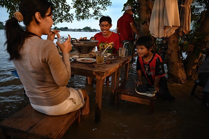 A family enjoying dinner at the Chaopraya Antique Cafe, as flood water from the Chao Phraya River surges into the restaurant, in Nonthaburi province north of Bangkok.