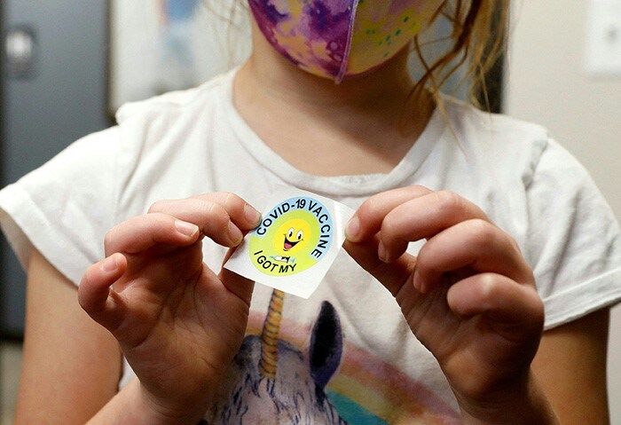 A 6 year-old child holds a sticker she received after getting the Pfizer-BioNTech Covid-19 vaccine.