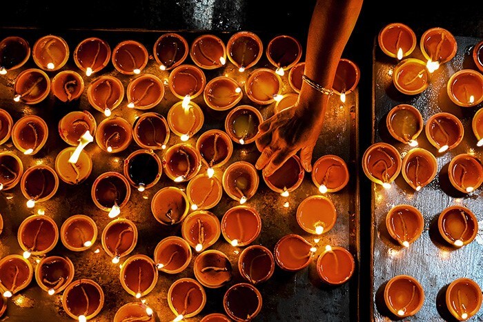 A Hindu devotee holds an oil lamp while offering prayers during Diwali.