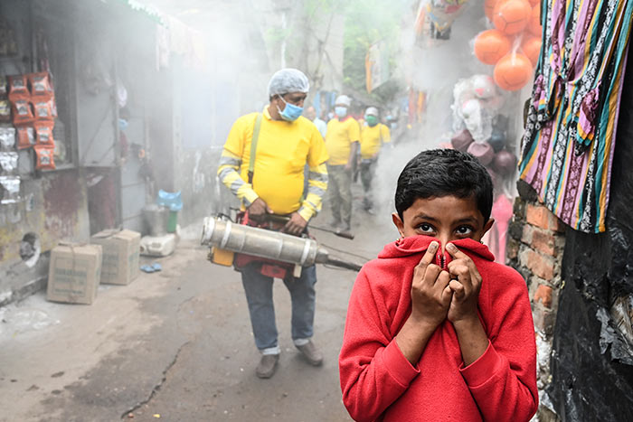 A child covers his face while a municipal worker fumigates a slum area as a preventive measure against mosquito-born diseases in Kolkata.