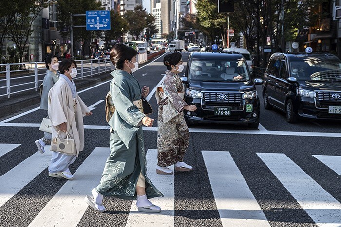 Women wearing traditional kimonos cross a street in Tokyo.