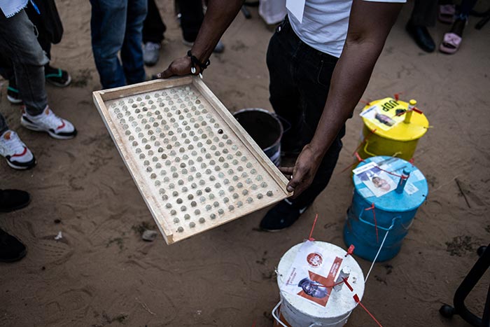 An election official displays the marbles out from the barrel during the count in Banjul, Gambia.