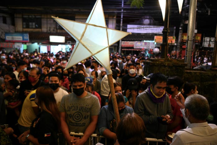 Roman Catholic devotees receive communion during a pre-dawn mass called "misa de gallo" at a church in Las Pinas, suburban Manila.