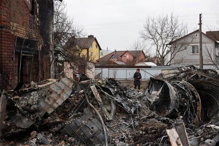 A woman walks around the wreckage of an unidentified aircraft that crashed into a house in a residential area in Kyiv.