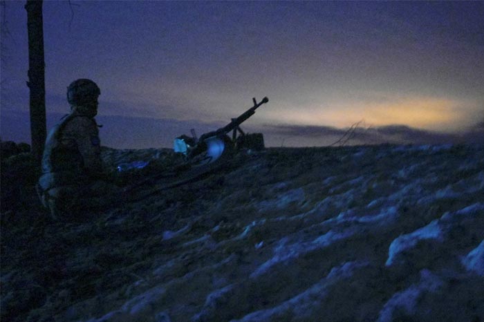 A Ukrainian serviceman sits on the ground at combat positions on the outskirts of Kharkiv, Ukrain.