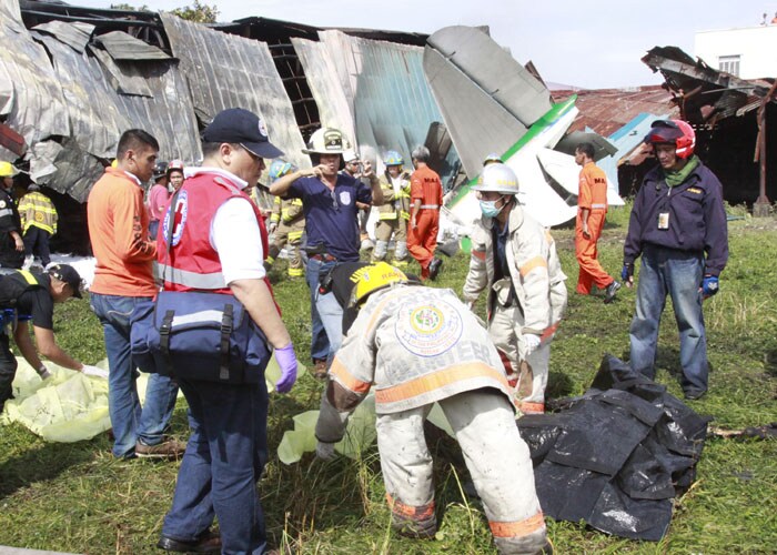 Rescuers cover the bodies of four people who were on board an airplane after it crashes into a&nbsp; warehouse Saturday, Oct. 17, 2009 in suburban Las Pinas south of Manila, Philippines. (AP Photo)