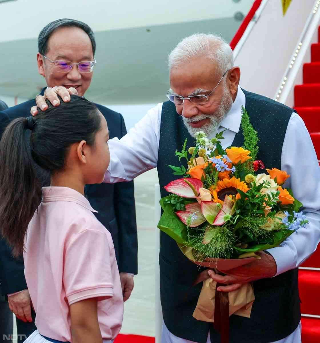 प्रधानमंत्री नरेंद्र मोदी शनिवार को चीन के तियानजिन पहुंचे, जहां उनका भव्य स्वागत किया गया. पीएम मोदी शंघाई सहयोग संगठन (एससीओ) शिखर सम्मेलन में भाग लेने के लिए चीन पहुंचे हैं. इस दौरान पीएम मोदी का बच्‍चों के प्रति विशेष स्‍नेह देखने को मिला. पीएम मोदी के चीन पहुंचने पर एक चीनी बच्‍ची ने उन्‍हें गुलदस्‍ता देकर स्‍वागत किया, जिसके बाद पीएम मोदी ने दुलार से उसके सिर पर हाथ फेरा.