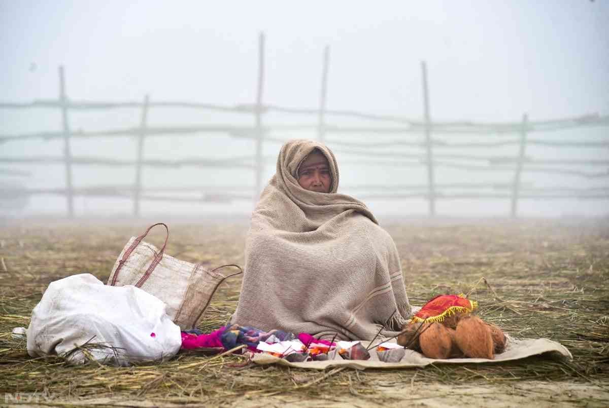 माघ मेले में संगम तट पर पूजा की सामग्री बेचती हुई एक महिला.