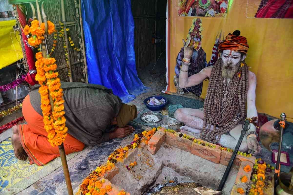 माघ मेले में एक साधु तपस्या करते हुए. अन्य लोग उन्हें प्रणाम कर रहे हैं...