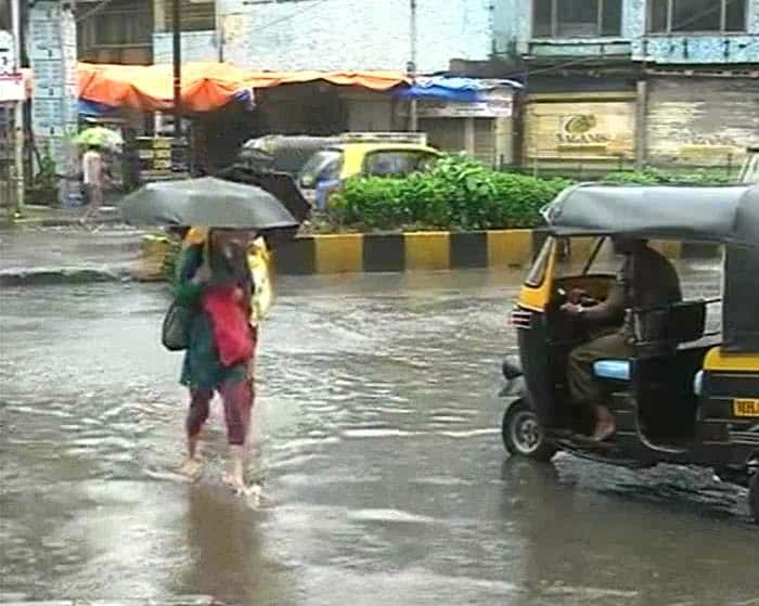 Seen here, a woman wades through ankle deep water in Bandra.