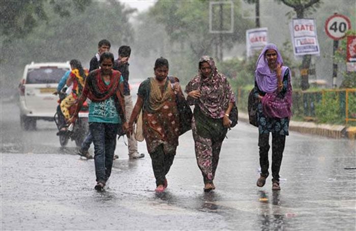 Seen here, a group of girls walk in the pouring rain in Ahmedabad.