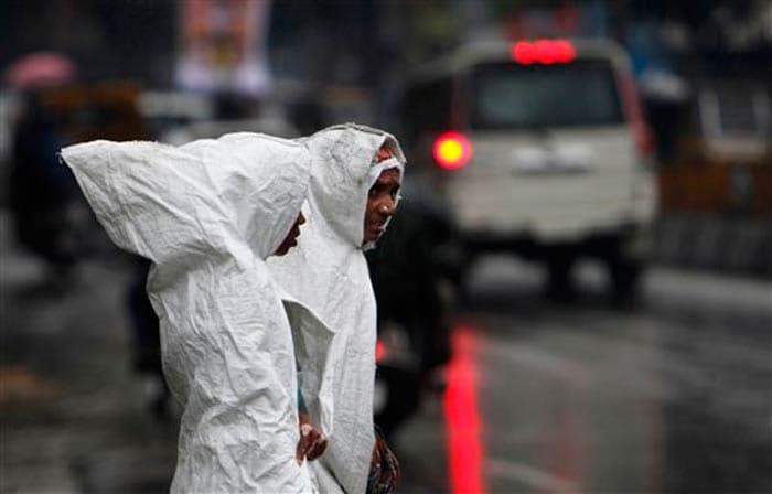 Seen here, two women cover themselves with plastic sheets to protect themselves from the rain in Hyderabad.