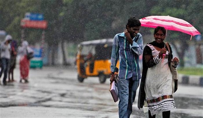 Seen here, a student holds an umbrella while walking with another in the rain in Hyderabad.