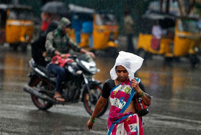 Seen here, a woman uses a plastic bag to cover her head as she crosses the road in Hyderabad.