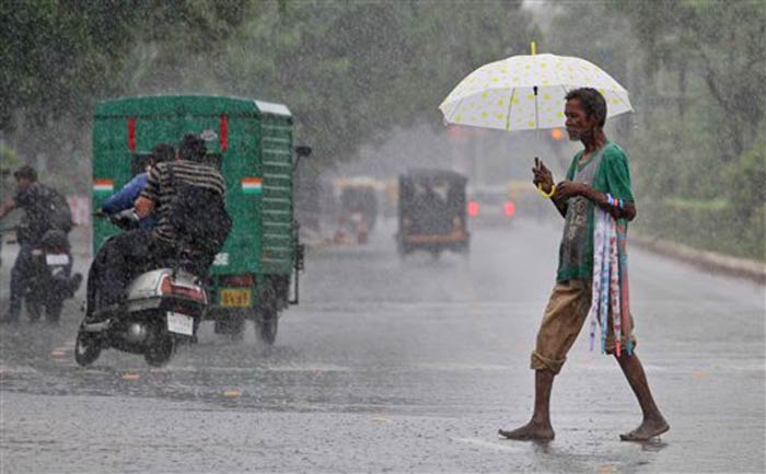 Seen here, an elderly man tries to sell some umbrellas in the rain in Ahmedabad.