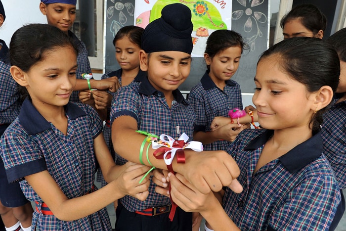 Indian school girls tie rakhi onto the wrist of a school boy on the eve of the Raksha Bandhan festival at Sun Valley Public School in Amritsar. (AFP Photo)