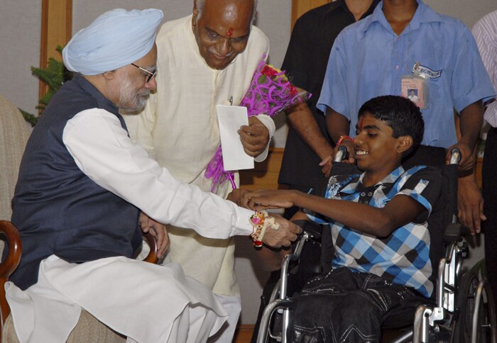 A physically disabled Indian boy ties a 'Rakhi' onto the wrist of Indian Prime Minister Manmohan Singh during a ceremony observing the festival of Raksha Bandhan at his residence in New Delhi. (AFP Photo)