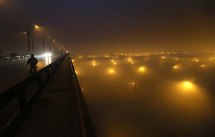 In this January 12 photo, a cyclist rides over a bridge as the camp and festival ground is enveloped in a morning fog at Sangam in Allahabad.