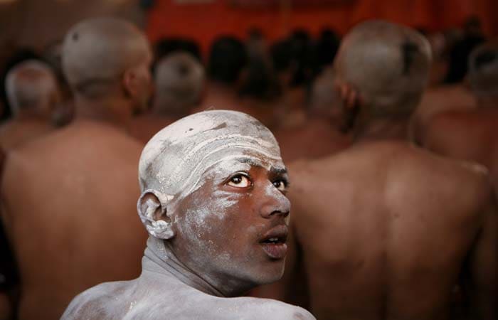 In this Feb 27 photo, a Naga Sadhu watches as other men of the Juna Akhara sect take the holy dip at Sangam, the confluence of the Ganges and Yamuna River during the Maha Kumbh festival in Allahabad.