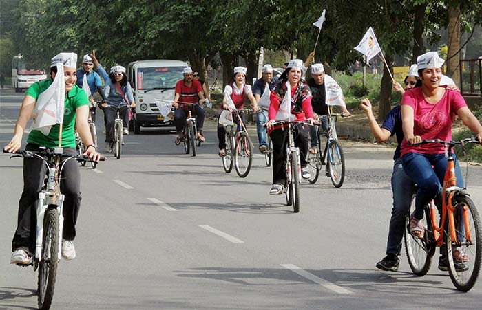 Women supporters of AAP ride on bicycles during campaigning.