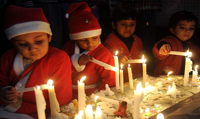 Children dressed as Santa Claus light up candles as they offer prayers on the eve of Christmas Day at St Paul's church in Amritsar on December 24.((Photo courtesy: AFP)