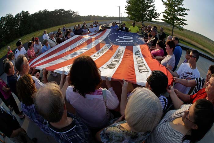 Visitors to the Flight 93 National Memorial participate in a sunset ceremony with a giant flag memorializing Flight 93.