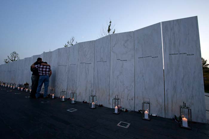 Visitors embrace in front of the wall containing the 40 names of the crew and passengers of Flight 93 at the Flight 93 National Memorial during a candlelight remembrance.